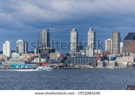 A water taxi cruises across Elliott Bay in front of the Seattel skyline. Royalty-Free Stock Photo #1952084248