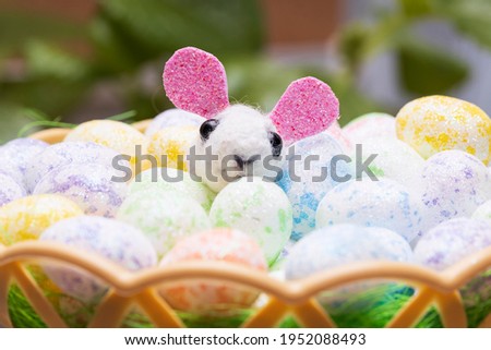 funny toy hare with colored Easter eggs in a basket. High quality photo