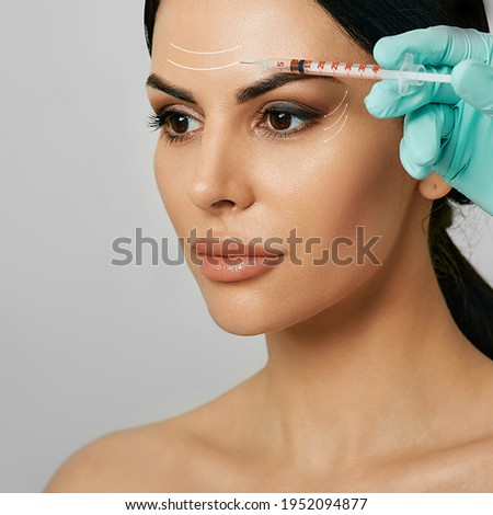 Botulinum toxin injections in a woman's forehead for blocking mimic wrinkles. Beautiful face with arrows, wrinkles removal concept Royalty-Free Stock Photo #1952094877