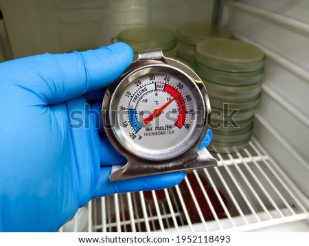 Refrigerator thermometer with colorful food in cold storage unit. Refrigeration safety gauge displaying safe food temperature.