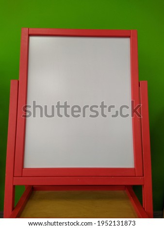 blank magnetic whiteboard against a green wall