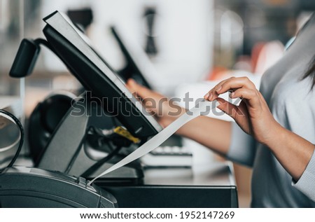 saleswoman or shopgirl printing a receipt or invoice for a customer, sales time, discount period, POS concept Royalty-Free Stock Photo #1952147269