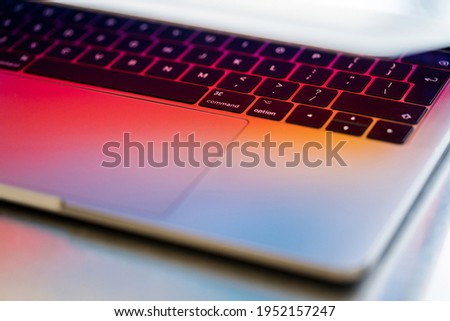 Close up of laptop partially open with colorful prism light and keyboard