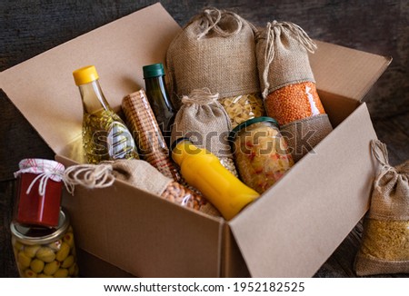 Volunteer with box of food for poor. Donation concept. Many foods in the package. 