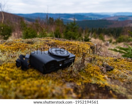 the camera is lying in the woods on a background of blurred forest