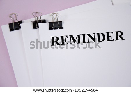 reminder the text is written on a white piece of paper and a pink background. word