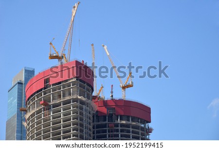 Construction of high-rise building with  Tower  cranes on clear sunny day