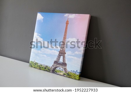 Canvas print stretched on frame with gallery wrap. Photography with Paris Eiffel Tower cityscape on white surface and grey wall background, photo printed on canvas, side view