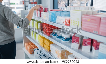 Pharmacy Drugstore: Anonymous Woman Chooses and Picks the Best Medicine Package, Supplemen Box, Drugs, Pills of the Shelf, She wants to Buy it. Modern Pharma Store Health Care Products Royalty-Free Stock Photo #1952232043