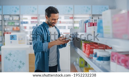 Pharmacy Drugstore: Portrait of Handsome Latin Man Choosing to Buy Medicine Browsing through the Shelf, Successfully finds what he Needs, Smiles Happily. Modern Pharma Store Health Care Products Royalty-Free Stock Photo #1952232238