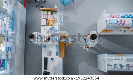 Pharmacy Drugstore Checkout Cashier Counter: Pharmacist Service Diverse Group of Customers Paying with Contactless Cards, Smartphones for Medicine, Vitamins, Health Care Products. Top View Shot Royalty-Free Stock Photo #1952243554