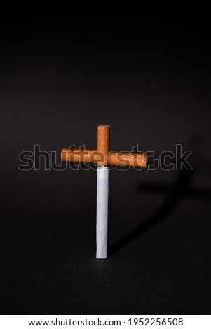 Cross from cigarettes on a black background. Symbol of death from smoking