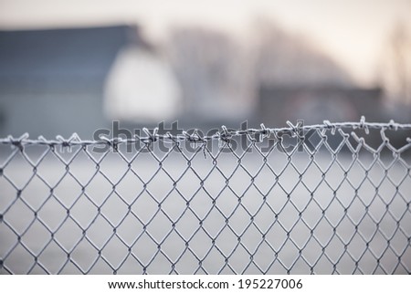 Beautiful composition of old frozen wire fence and old farm house in background with a low depth of field