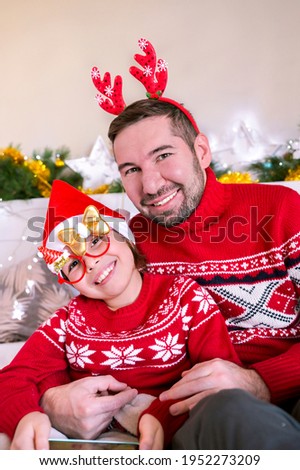 Little daughter in Santa hat with dad in a room decorated for Christmas. Happy family celebrating winter holidays. High quality photo
