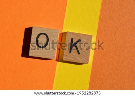OK, abbreviation for okay, wooden alphabet letters isolated on orange and yellow