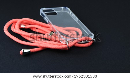 Mobile Phone Transparent Case and Orange Rope with Isolated Black Background
