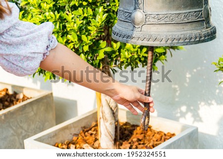 Woman hand rings the old bell for Make a wish in the Wat Saket Golden Mount Temple famous , is a Buddhist temple in Pom Prap Sattru Phai district, Bangkok. Royalty-Free Stock Photo #1952324551