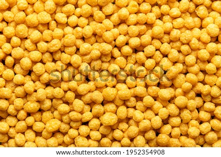 Honey pops breakfast cereals background, flat lay. Full frame with cornflakes. Delicious corn cereal balls. Macro image with yellow round cereals. Royalty-Free Stock Photo #1952354908