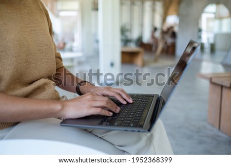 Closeup image of a woman working and typing on laptop computer keyboard in cafe