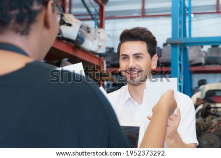 Man work with woman, giving paper note. Diversity of two people, caucasian business manager giving white paper note to black African worker woman in factory-warehouse
