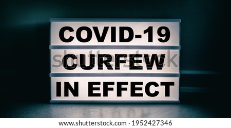 Curfew in effect text message on lit lightbox for covid coronavirus pandemic. Warning at night.