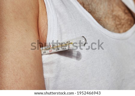 Mercury thermometer under a man's armpit.