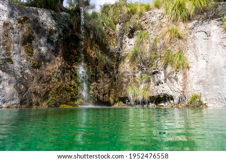 Pool with green water and a small waterfall from the rock. Mallorca. Spain.