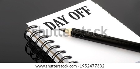 DAY OFF written text in a small notebook on black background