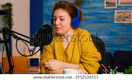 Famous influencer with headphones checking sound before live vlogging for social media, in home podcast studio. On-air online production internet broadcast show host streaming live content