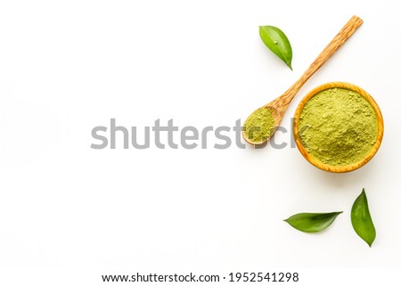 Henna powder in wooden bowl with green leaves. Herbal natural hair dye.
