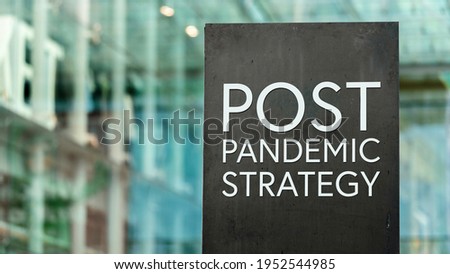 Post Pandemic Strategy sign in front of a modern office building	
