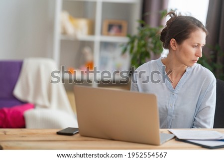 woman sitting at a desk at home working with a computer laptop is tired and bored at office work. unmotivated lazy brown-haired woman feels sleepy at a boring job and lack of sleep