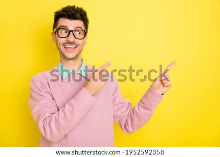 Photo of young happy smiling dreamy man in glasses point finger copyspace advertisement isolated on yellow color background
