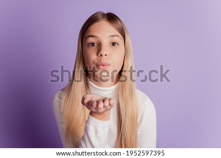 Photo of dreamy affectionate lady send air kiss wear white jumper posing on purple background