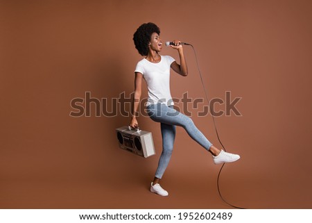 Photo of crazy girl dance sing mic hold boombox wear white t-shirt jeans footwear isolated brown color background