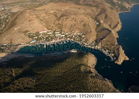 Resort village Balaklava in bay of Black sea with rocky coastline. Tourist place of Crimea. Aerial high altitude wide shot at summer sunny day