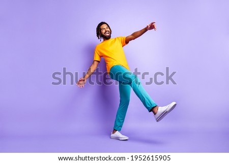 Full size photo of nice optimistic brunette hairdo guy dance wear orange t-shirt pants isolated on lilac color background
