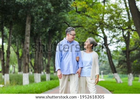 Happy old couple walking in the park arm in arm