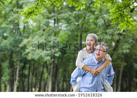 An elderly man carrying his wife in the park 