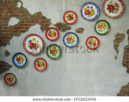 Zinc coated tray with flower pattern adorned on brick wall. Which is introduction of tray with local art to decorate building. Lampang Thailand.
