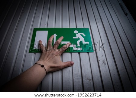 Person try escape from indoors. Hand push exit sign door. Crime horror concept.