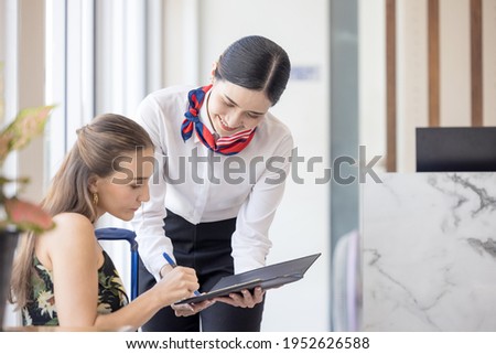 tourist woman going to fill and sign hotel check in registration form at reception counter, kundenservice when arrival destination for summer vacation