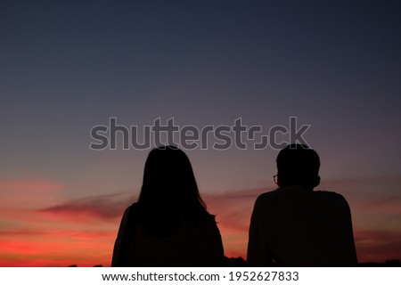 A couple of lovers were enjoying the beautiful sunset. Lovers silhouette. 