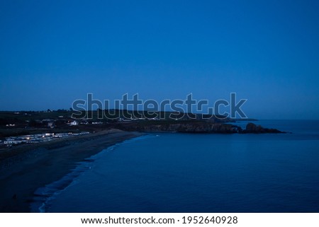 Irish Bunmahon beach in the twilight. Beach in the twilight, dark picture of a beach after sunset. Landscape with blue shades. Small town overlooking the sea at night. Beaches at night concept.