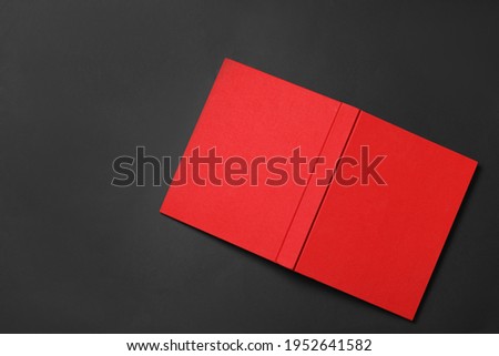 Book with red cover on black background, top view. Space for text