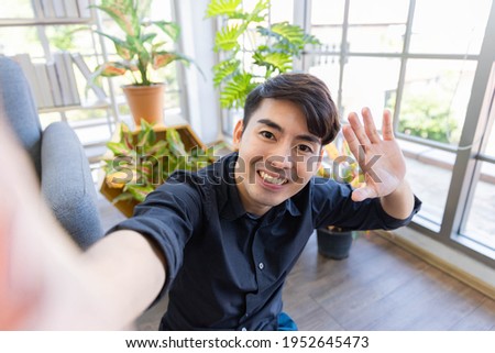 A handsome asian man relax and take selfie shot in living room in his house