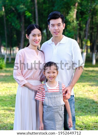 Happy family of three standing in the park smiling