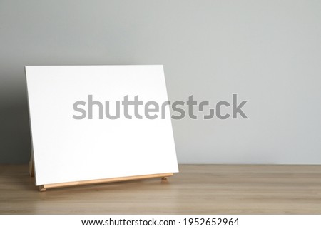 Wooden easel with blank canvas on table. Space for text