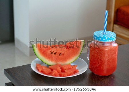 A picture of sliced and diced watermelon alongwith its juice in a mason jar on a hot sunny day.