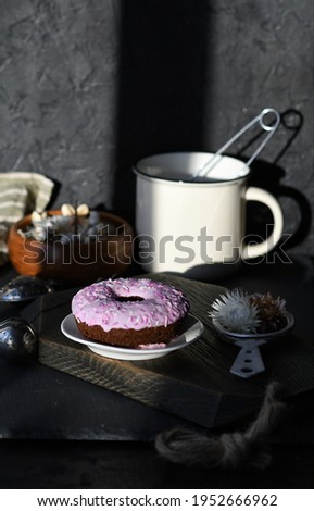 PINK DONUT ON A WHITE PLATE.SUNLIGHT THROUGH THE WINDOW. BLACK BACKGROUND
